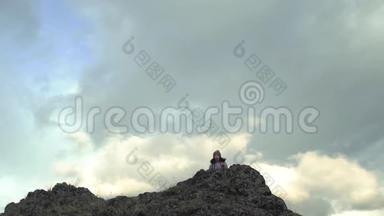 兴奋的时髦女孩站在高高的山顶上自由举手，快乐的女旅行者的后景